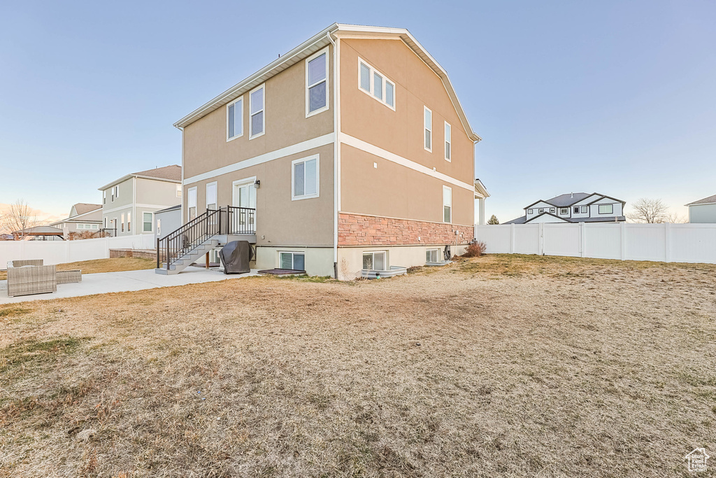 Rear view of house with a patio, a fenced backyard, and stucco siding