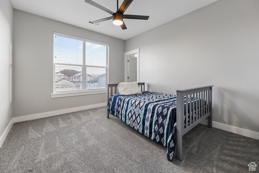 Bedroom with visible vents, baseboards, dark colored carpet, and a ceiling fan