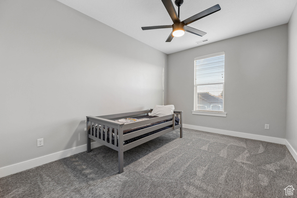 Bedroom with a ceiling fan, dark carpet, visible vents, and baseboards