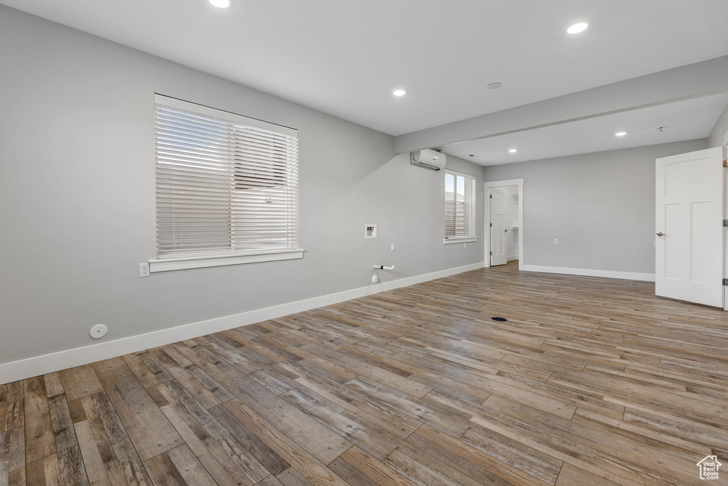 Spare room with baseboards, a wall unit AC, and light wood finished floors
