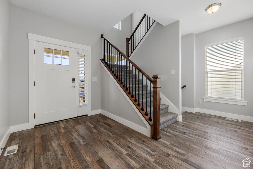Foyer featuring dark wood-type flooring, stairway, visible vents, and baseboards