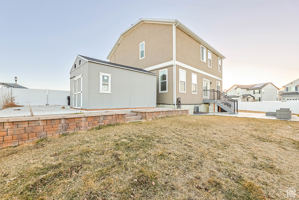 Rear view of house featuring a lawn, a patio area, a fenced backyard, and stucco siding
