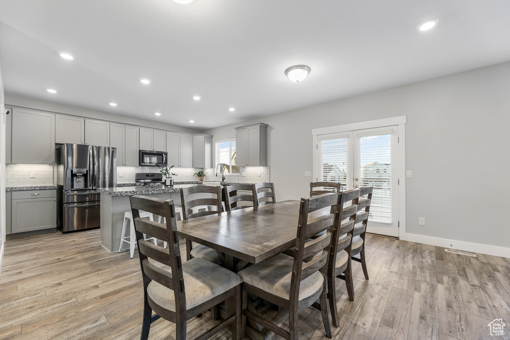 Dining room with light wood-type flooring, baseboards, and recessed lighting