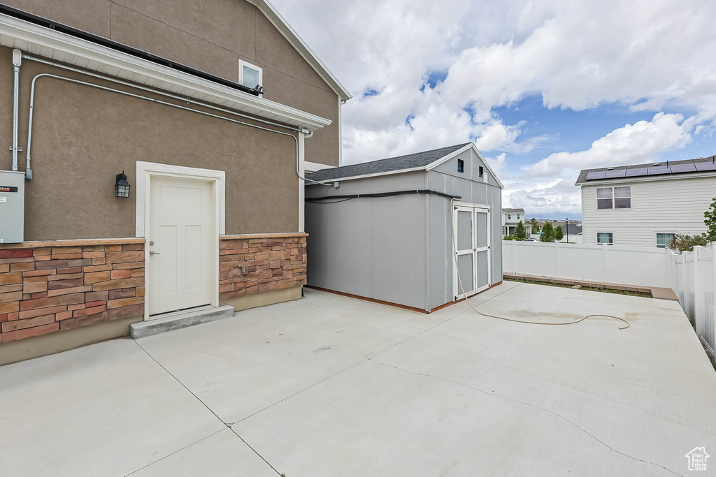 View of patio featuring a storage shed, an outbuilding, and fence