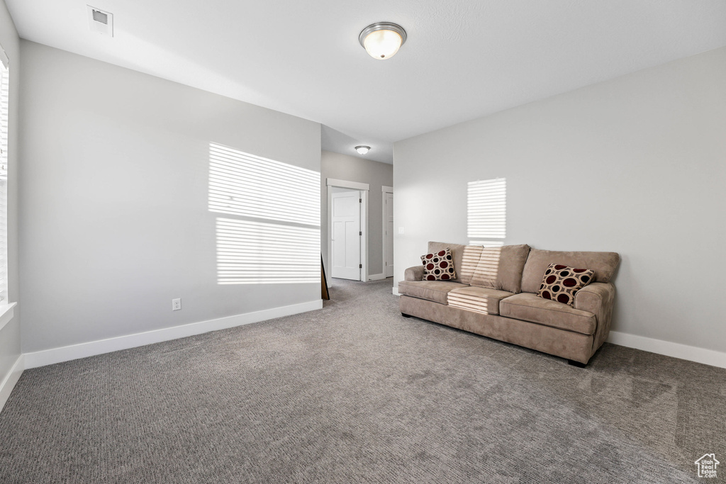 Carpeted living area featuring baseboards and visible vents
