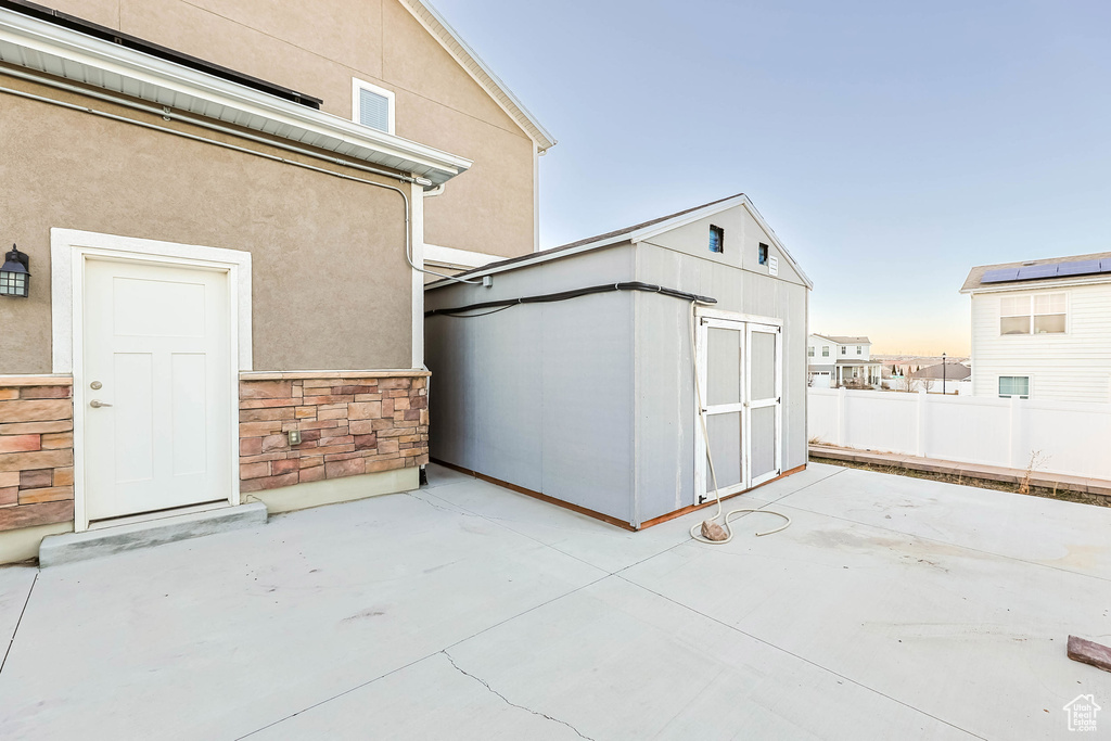 View of patio / terrace featuring an outbuilding, fence, and a storage unit