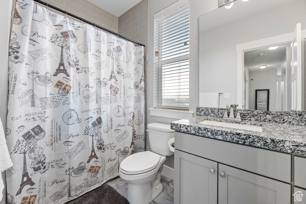 Bathroom featuring toilet, a shower with shower curtain, and vanity