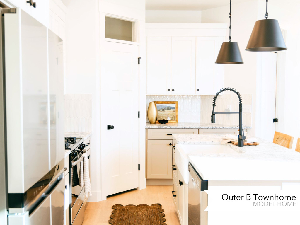 Kitchen with dishwashing machine, decorative light fixtures, white cabinets, light stone countertops, and stainless steel range with gas stovetop
