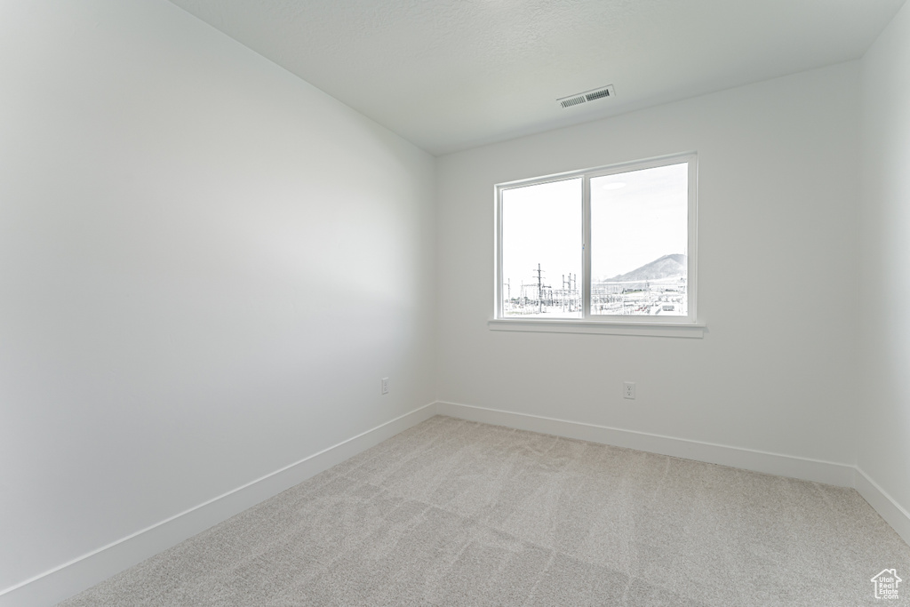 Empty room with baseboards and light colored carpet