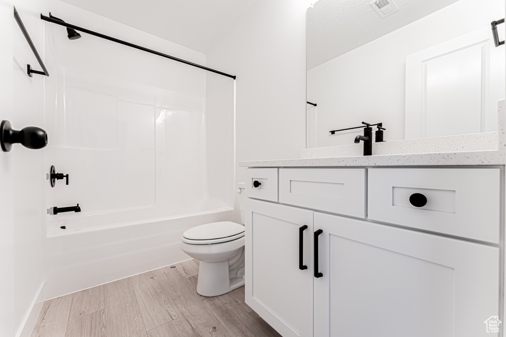 Full bathroom featuring toilet, vanity, shower / tub combination, and wood finished floors