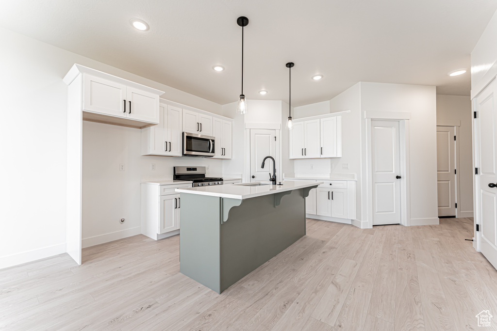 Kitchen featuring stainless steel appliances, a sink, baseboards, light wood-style flooring, and recessed lighting