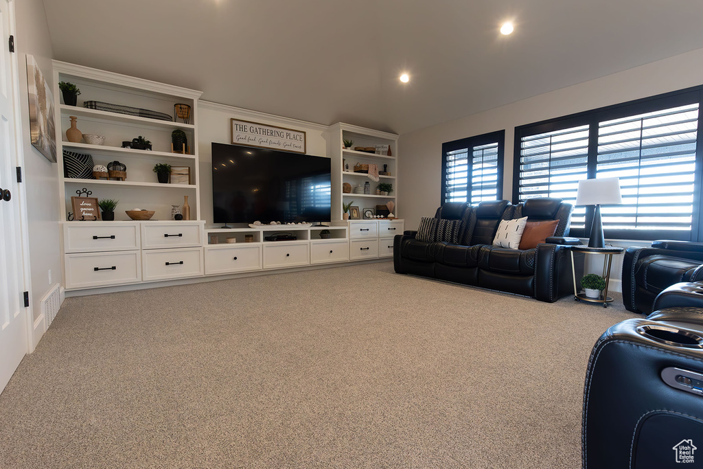 Carpeted living room with lofted ceiling, visible vents, and recessed lighting
