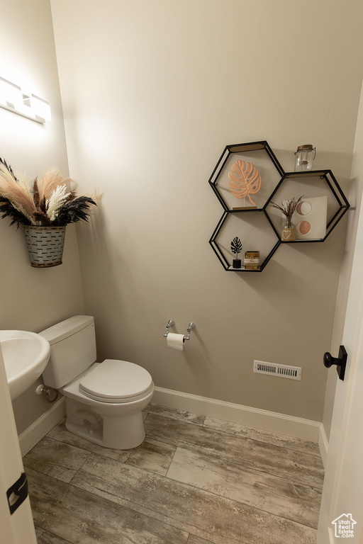 Half bath featuring toilet, visible vents, baseboards, and a sink