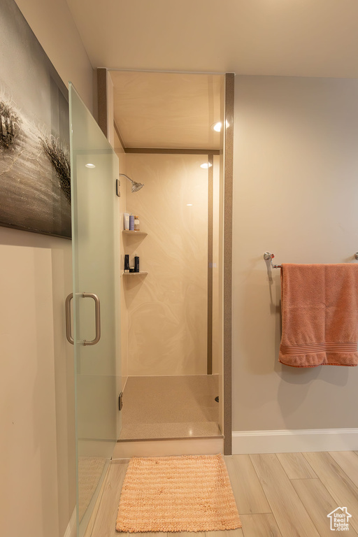 Bathroom with a shower stall, baseboards, and wood finished floors