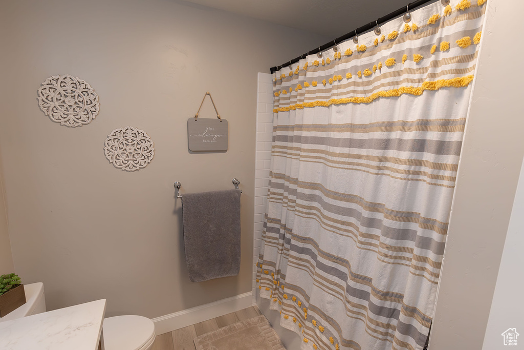Full bathroom featuring toilet, a shower with shower curtain, wood finished floors, vanity, and baseboards