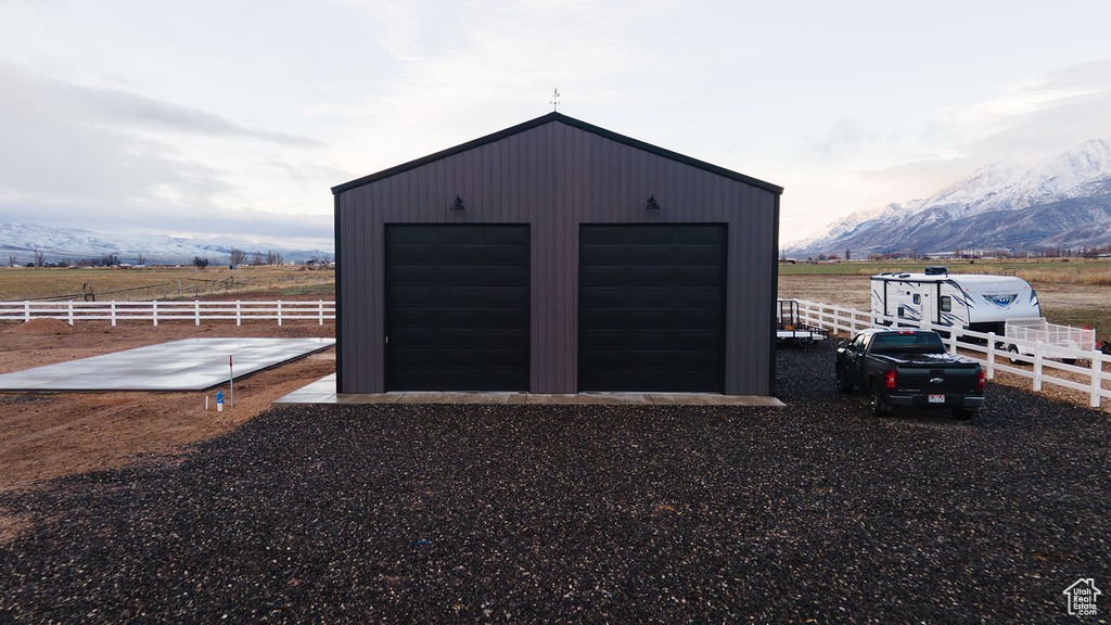 View of outdoor structure with an outbuilding, a rural view, a mountain view, and fence
