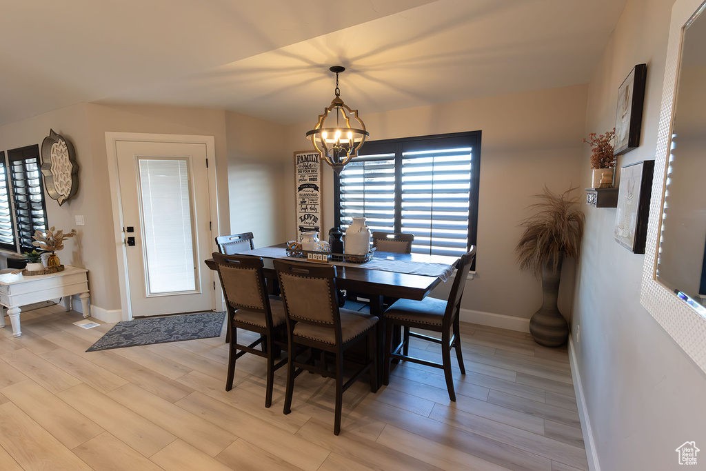 Dining area featuring baseboards, light wood-type flooring, and an inviting chandelier