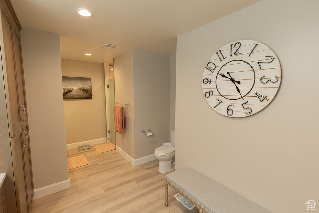 Full bathroom featuring baseboards, toilet, wood finished floors, walk in shower, and recessed lighting