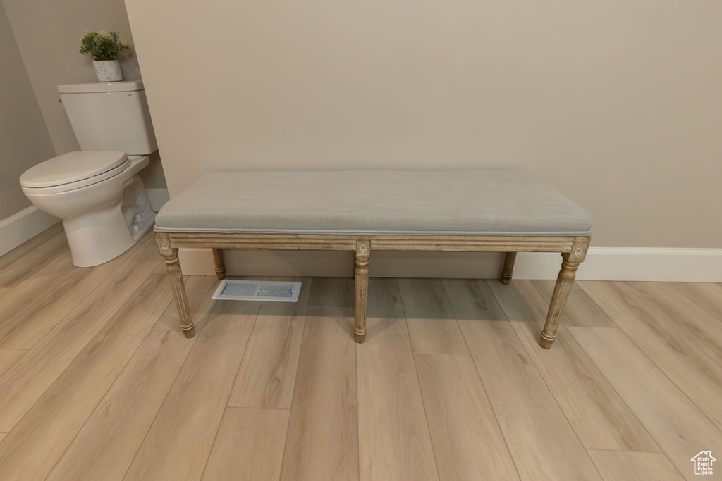 Room details featuring toilet, wood finished floors, visible vents, and baseboards