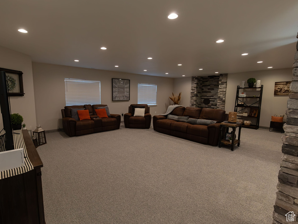 Living area featuring baseboards, a stone fireplace, recessed lighting, and light colored carpet