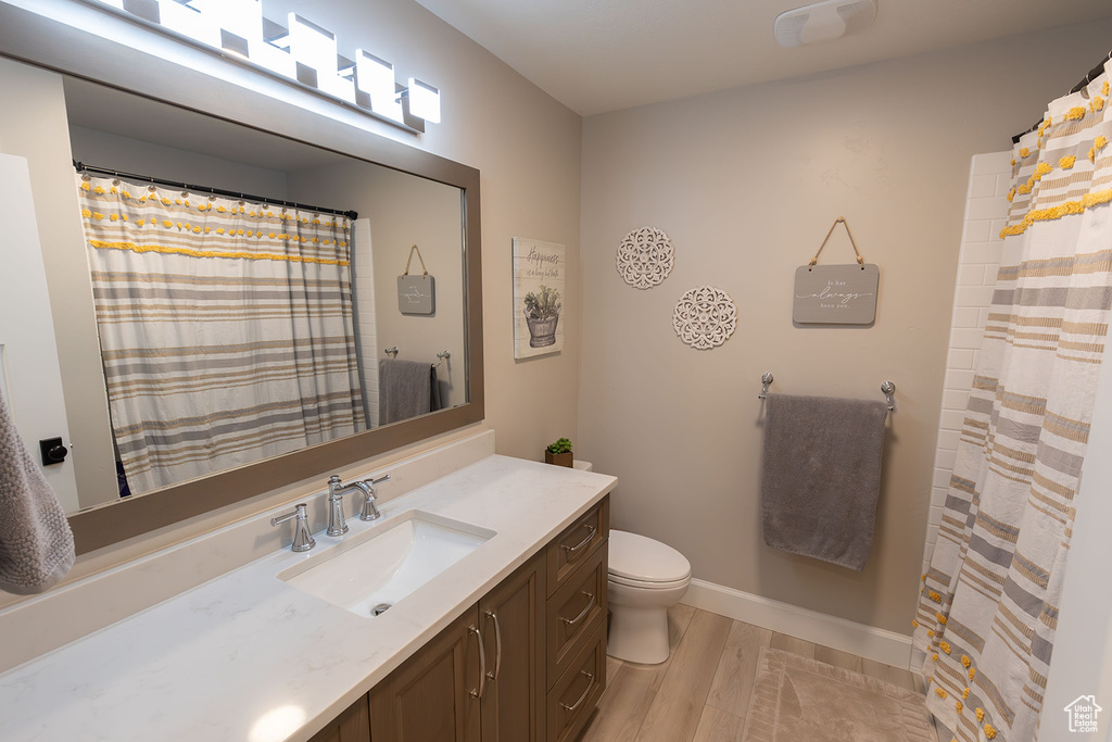Bathroom featuring toilet, baseboards, wood finished floors, and vanity