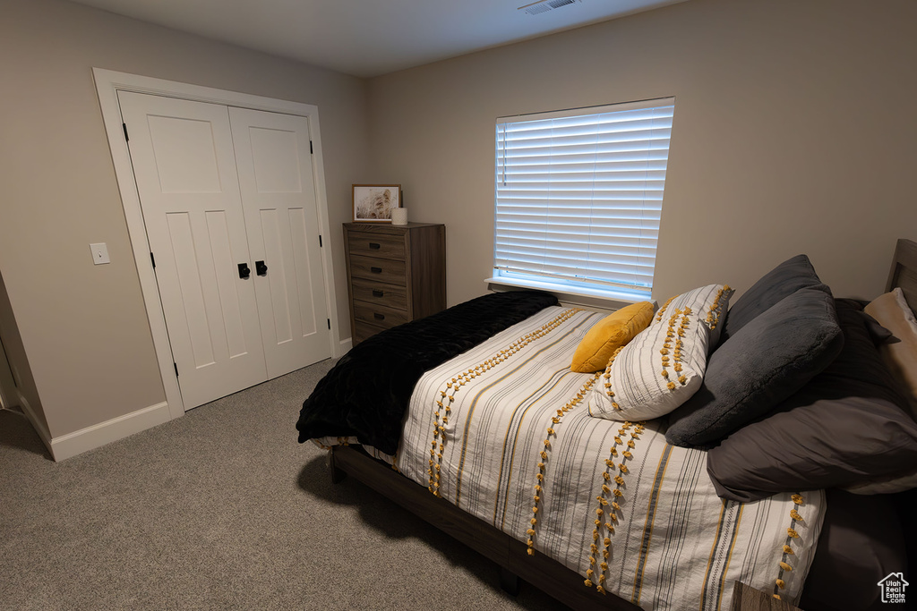 Carpeted bedroom with a closet, visible vents, and baseboards