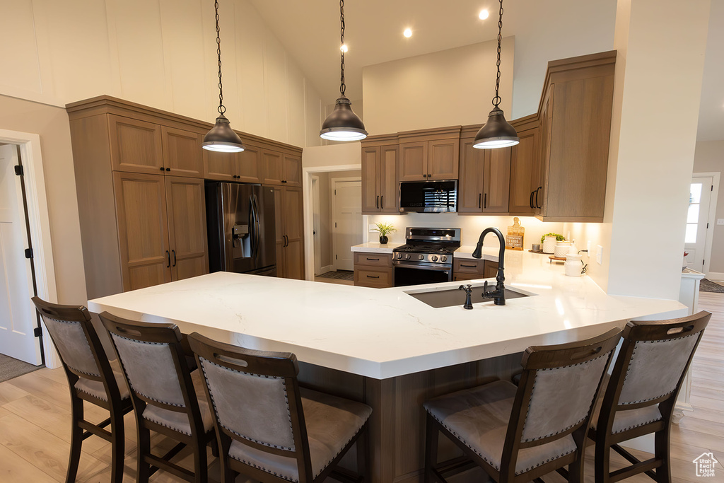 Kitchen featuring a peninsula, a high ceiling, stainless steel appliances, light countertops, and a sink