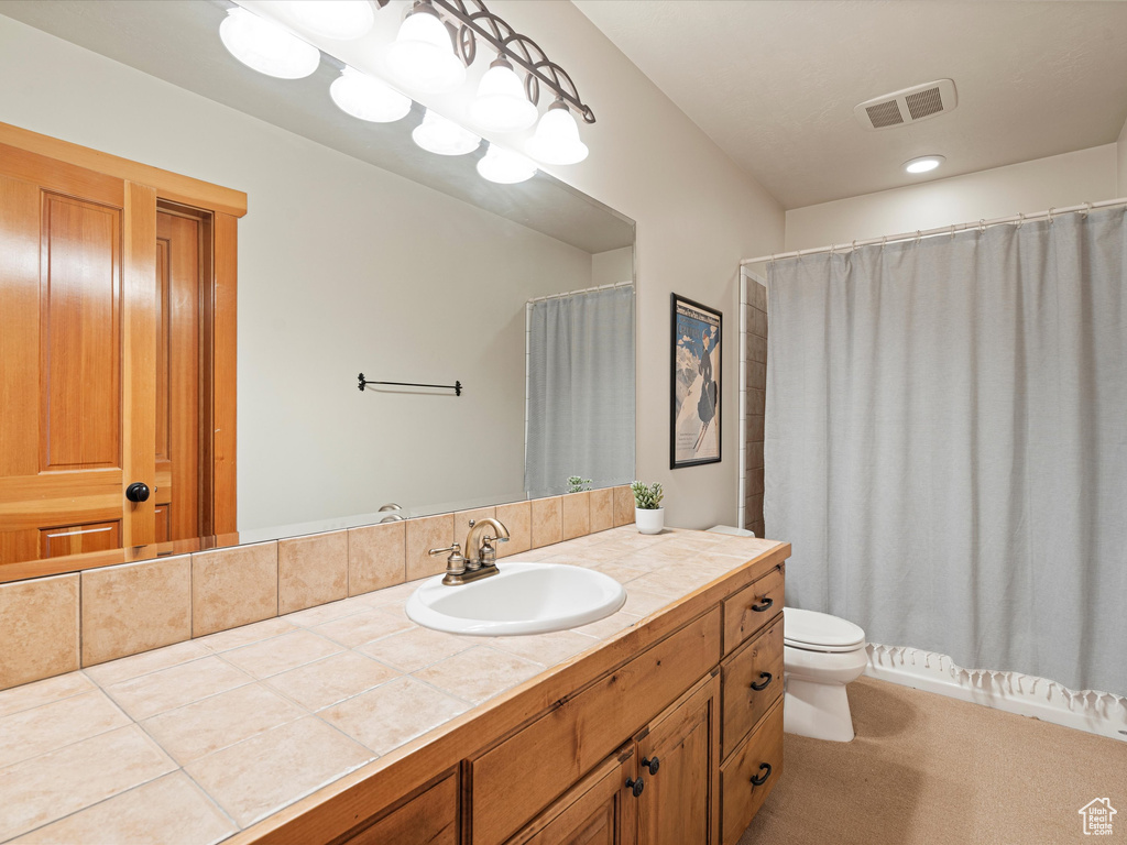 Bathroom with toilet, visible vents, and vanity