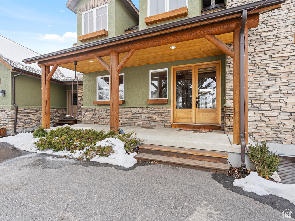 Doorway to property with stone siding, french doors, and stucco siding