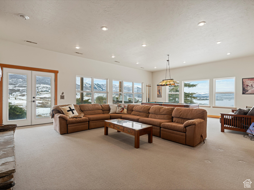 Living room featuring french doors, visible vents, light carpet, and a textured ceiling