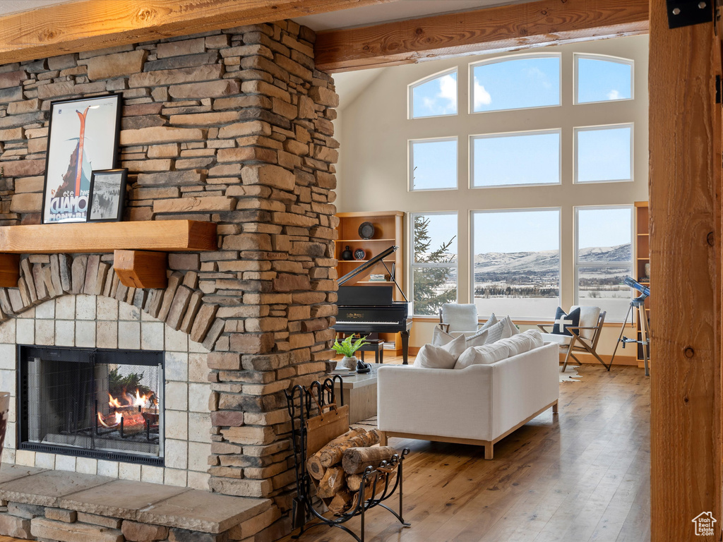 Living room with high vaulted ceiling, a mountain view, a fireplace, wood finished floors, and beamed ceiling