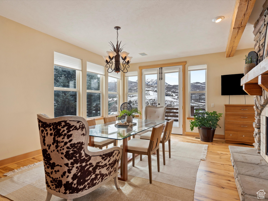 Dining area featuring light wood-style floors, beam ceiling, a notable chandelier, and baseboards