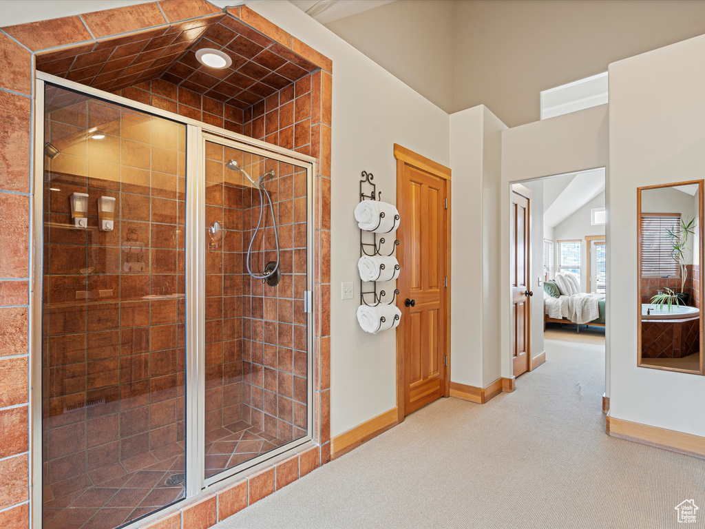 Ensuite bathroom featuring a stall shower, ensuite bath, baseboards, and vaulted ceiling