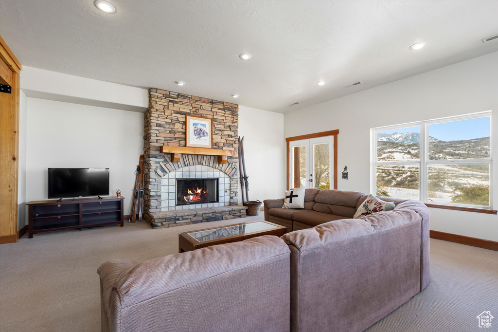 Living area featuring baseboards, a stone fireplace, french doors, carpet floors, and recessed lighting