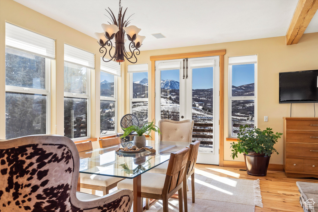 Sunroom with a notable chandelier, beam ceiling, and a healthy amount of sunlight