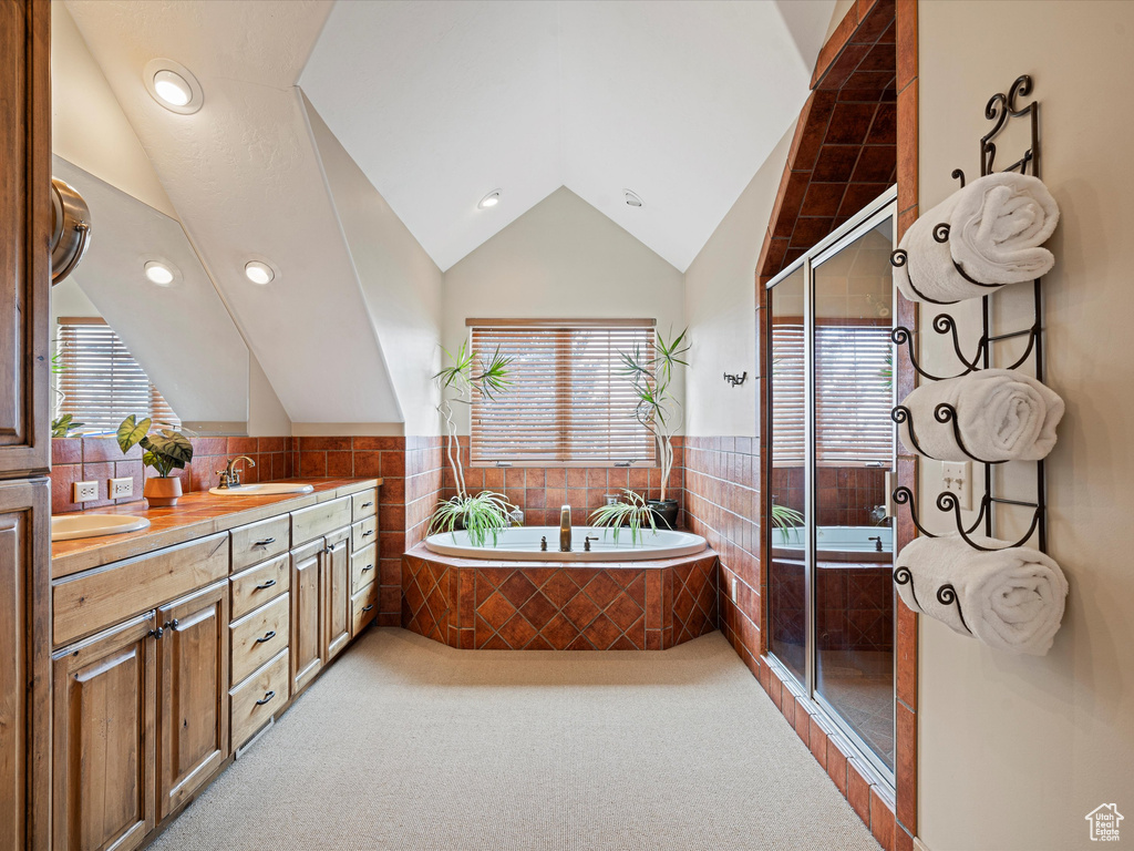 Full bathroom with lofted ceiling, a sink, a shower stall, and a bath