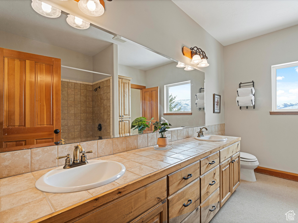 Full bathroom featuring double vanity, a sink, toilet, and baseboards