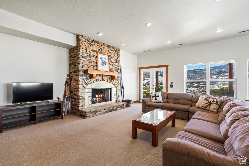 Living room with carpet, a textured ceiling, french doors, a fireplace, and recessed lighting