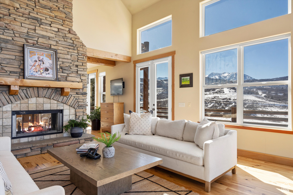 Living room featuring a towering ceiling, a fireplace, baseboards, and wood finished floors