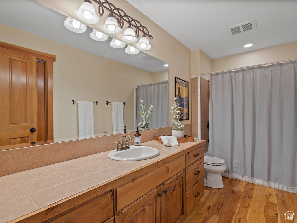 Full bathroom featuring toilet, vanity, wood finished floors, and visible vents