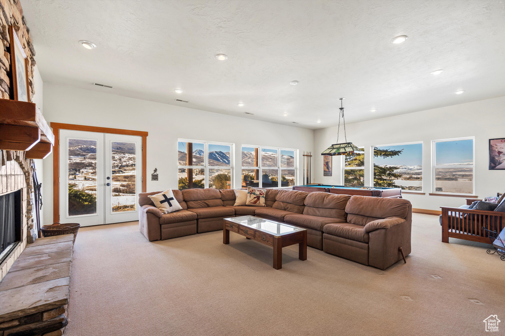 Living area with recessed lighting, light colored carpet, a fireplace with raised hearth, and a textured ceiling