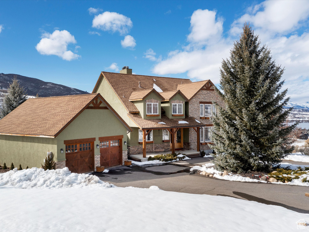 View of front of house with an attached garage, a mountain view, aphalt driveway, and stucco siding