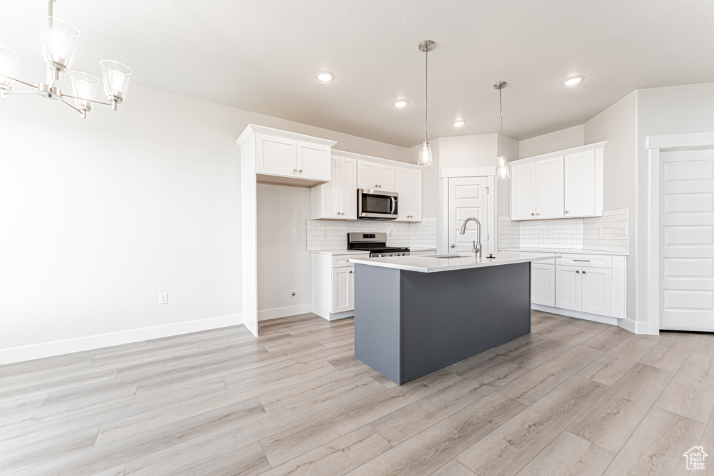 Kitchen with stainless steel appliances, white cabinets, light countertops, decorative backsplash, and recessed lighting