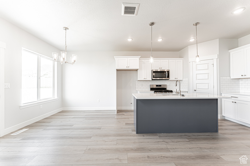 Kitchen with appliances with stainless steel finishes, recessed lighting, light countertops, white cabinets, and backsplash
