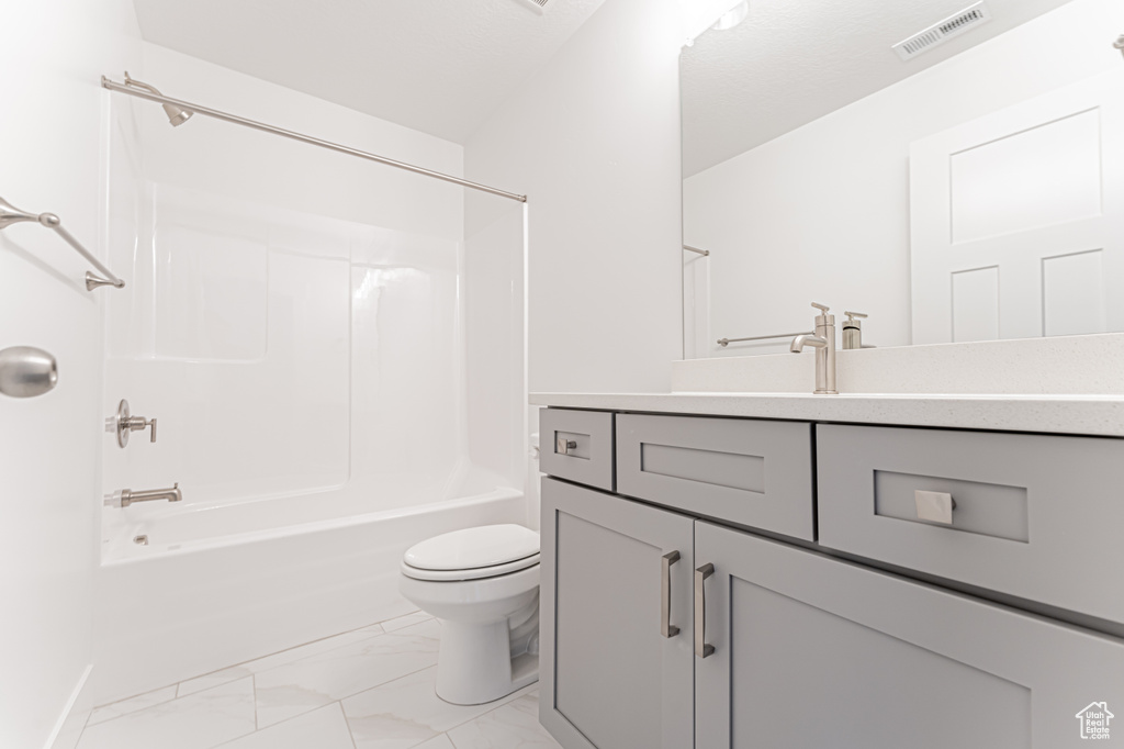 Bathroom with marble look tiles, toilet, vanity, bathtub / shower combination, and baseboards