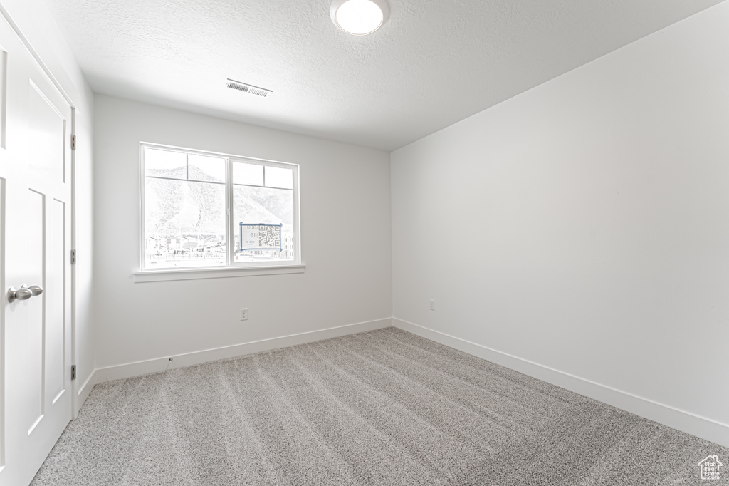Unfurnished room featuring a textured ceiling, carpet, and baseboards