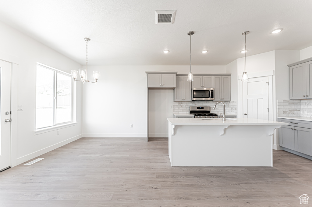 Kitchen with appliances with stainless steel finishes, gray cabinetry, light countertops, backsplash, and recessed lighting