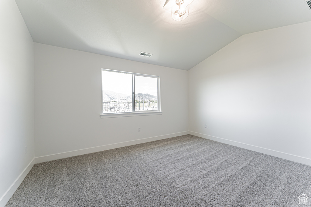 Spare room with lofted ceiling, carpet, and baseboards