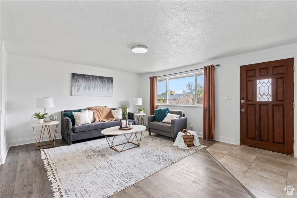 Living room featuring a textured ceiling, wood finished floors, and baseboards