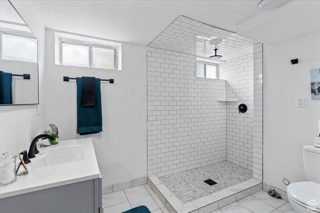 Full bathroom featuring toilet, tiled shower, and a healthy amount of sunlight